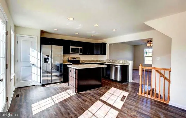 a kitchen with stainless steel appliances kitchen island granite countertop a refrigerator and a stove top oven