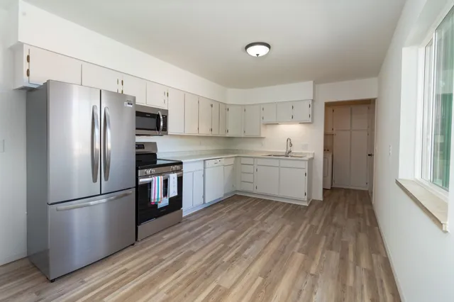 a kitchen with a refrigerator a sink and dishwasher with wooden floors