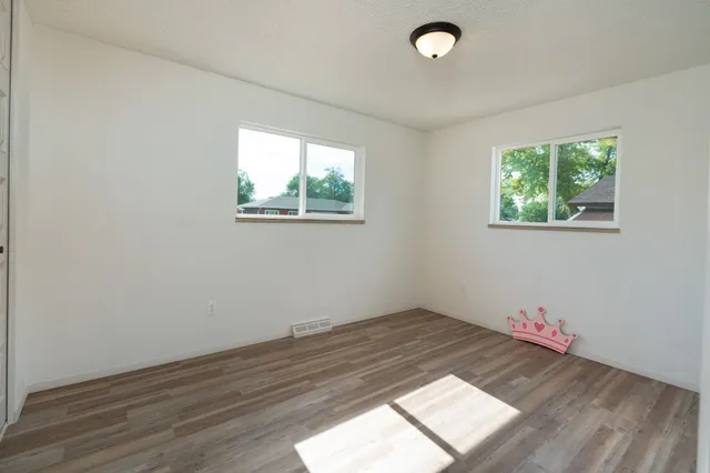 an empty room with wooden floor and window