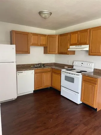 a kitchen with granite countertop wooden floors and white stainless steel appliances