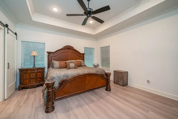 a bedroom with a bed and dresser with wooden floor