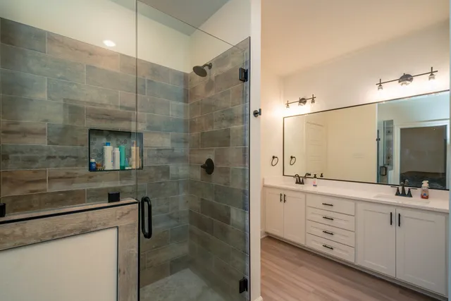 a bathroom with a double vanity sink a toilet and shower