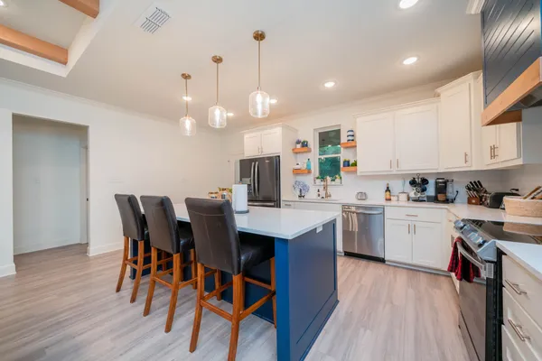 a kitchen with a dining table chairs wooden floor cabinets appliances and a window