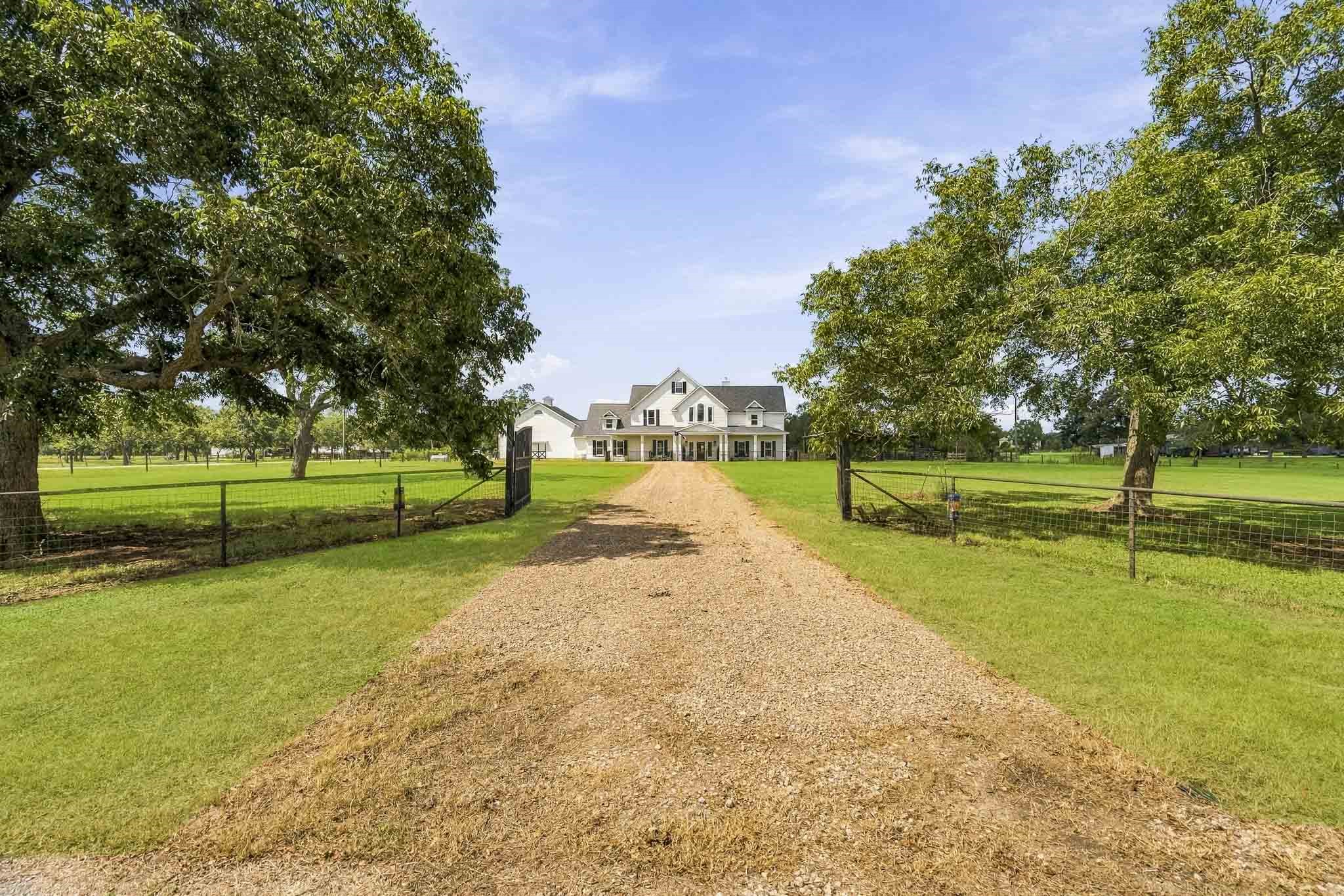 3103 Brundrett Road Wallis, TX 77485 - Photo 5 of 45 The property is fully fenced, cross-fenced and welcomes you through an elegant wrought iron private gate, opening to a picturesque drive that sets the tone for the estate's serene charm. As the scenic drive gracefully winds through the property, it leads to the detached 3-Car Garage with an oversized door, providing the perfect storage for a boat or RV. For added convenience and accessibility, a second gated entrance is located along the side of the home.