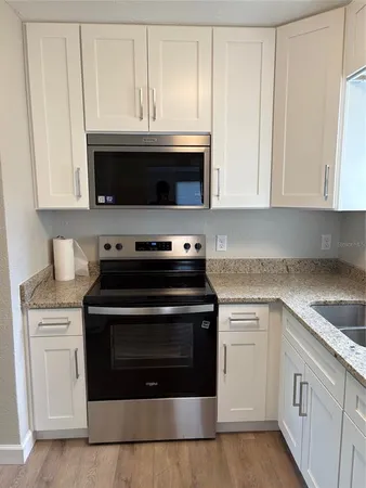a kitchen with granite countertop white cabinets and stainless steel appliances