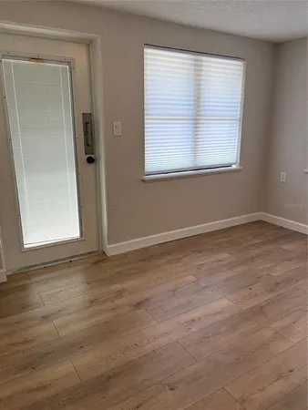 a view of an empty room with wooden floor and a window