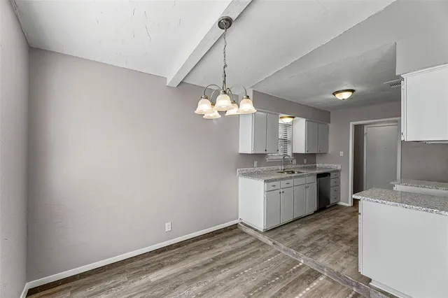 a view of a kitchen with a sink and dishwasher with wooden floor