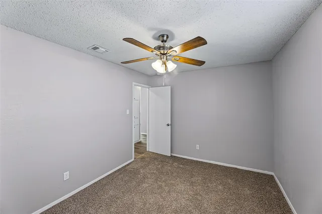 a view of an empty room and a ceiling fan and window