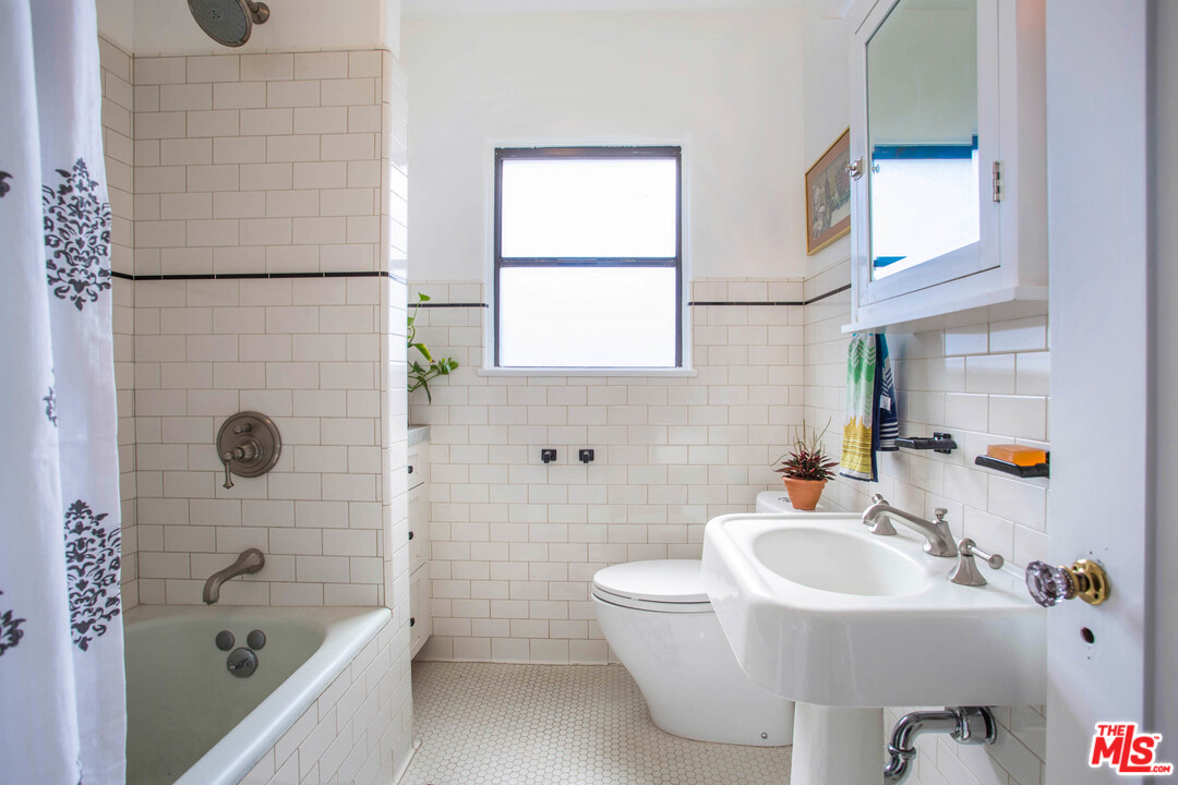 4541 Round Top Drive Los Angeles, CA 90065 - Photo 23 of 40 a bathroom with a sink a toilet a mirror a bathtub and shower