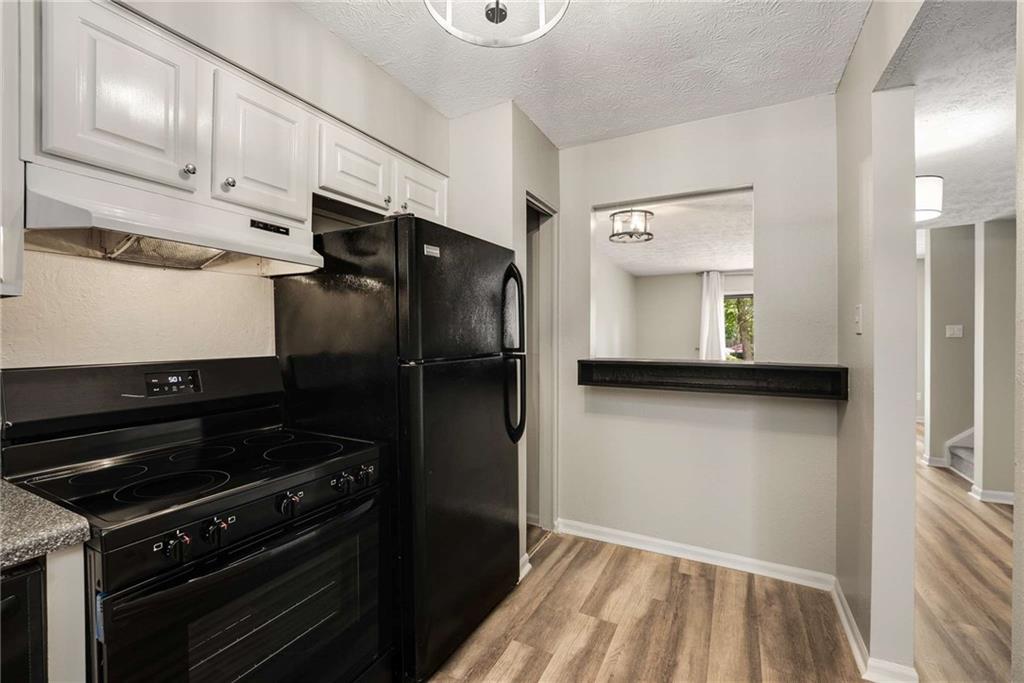 6170 Woodland Road Northwest Peachtree Corners, GA 30092 - Photo 12 of 27 a kitchen with a refrigerator stove and cabinets