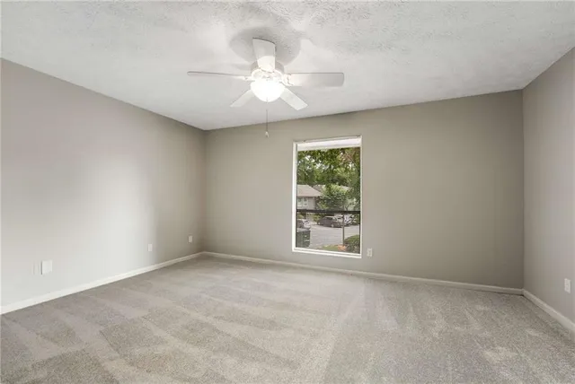 an empty room with windows and fan