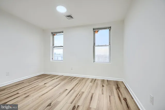 an empty room with wooden floor and windows
