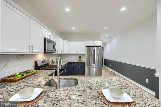 a kitchen with stainless steel appliances granite countertop a sink a refrigerator and a granite counter tops