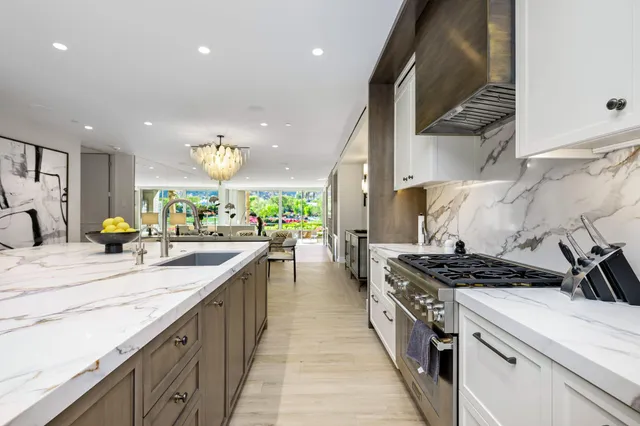 a kitchen with kitchen island stainless steel appliances a sink a counter top space stove and cabinets
