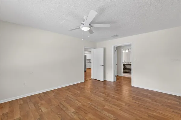 an empty room with wooden floor fan and windows