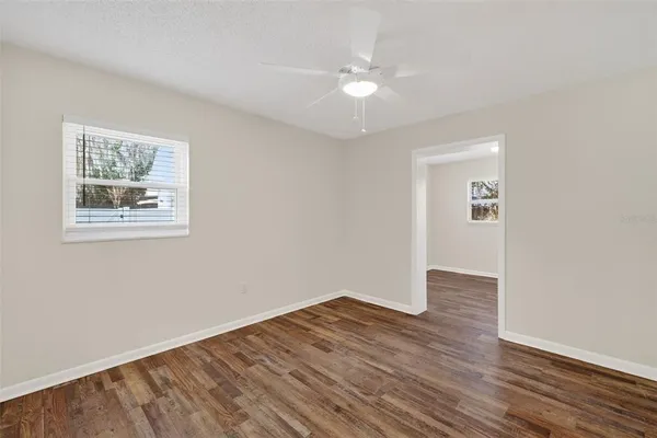 an empty room with wooden floor and a ceiling fan