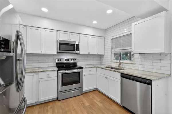 a kitchen with stainless steel appliances granite countertop a sink stove microwave and refrigerator