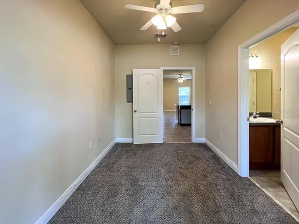 an empty room with a chandelier fan and a bathroom