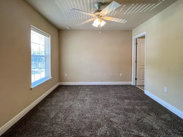 an empty room with windows and fan