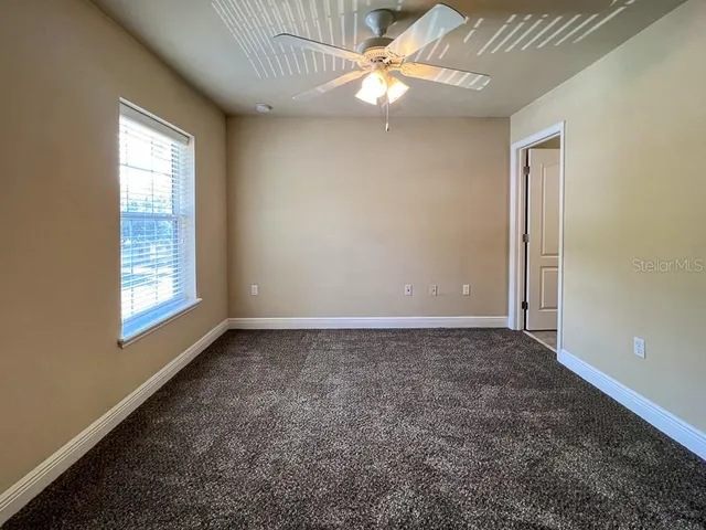 an empty room with windows and fan