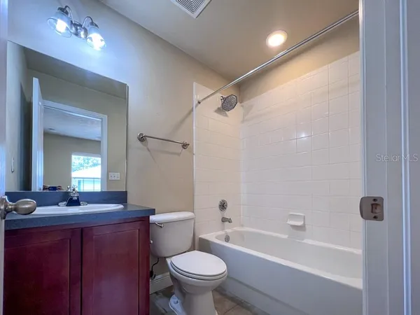 a bathroom with a bathtub shower sink vanity mirror and toilet