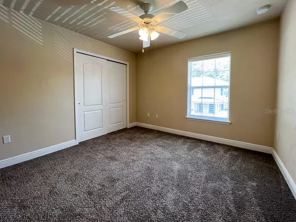 an empty room with windows and fan