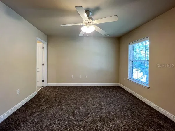 an empty room with window and ceiling fan
