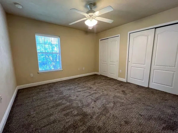 an empty room with windows and fan