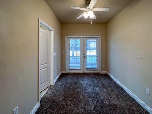 en empty room with windows and ceiling fan