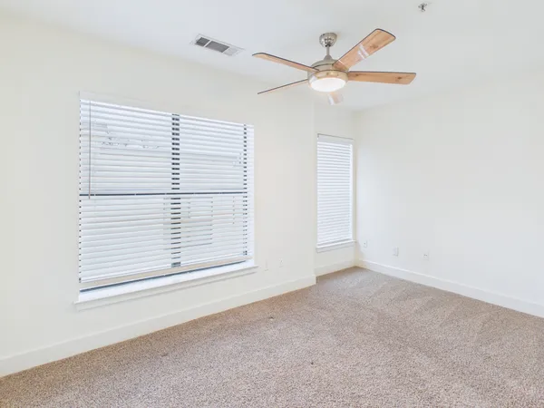 an empty room with a window and a ceiling fan