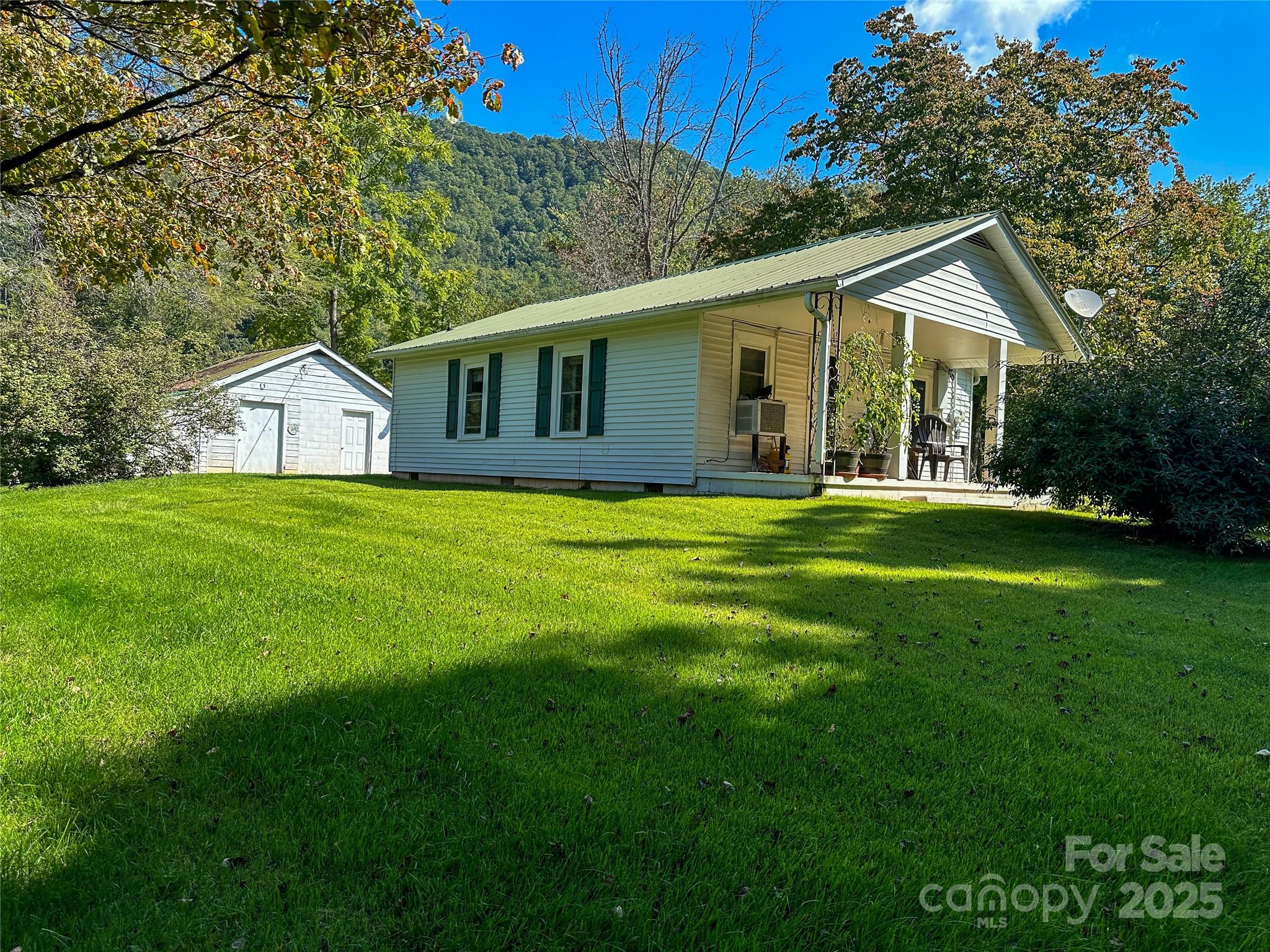 241 Canada Road Tuckasegee, NC 28783 - Photo 3 of 27 a house that is sitting in the grass with large trees and plants
