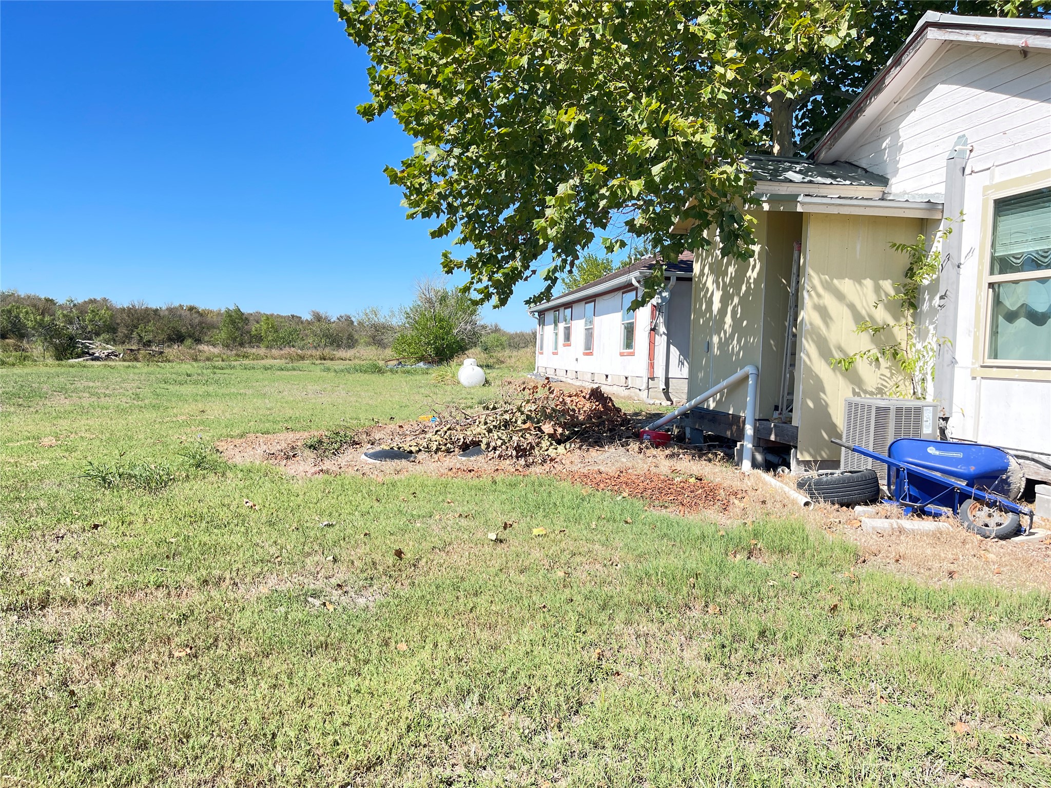 12212 Ballerstedt Road Elgin, TX 78621 - Photo 28 of 29 An open grassy yard borders the side of this traditional single-story home.