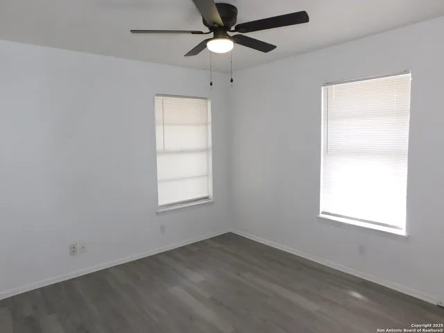 an empty room with a window and a fan