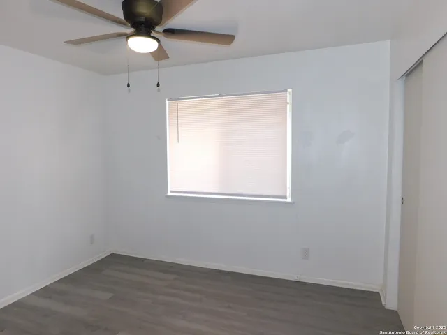 an empty room with a window and a fan