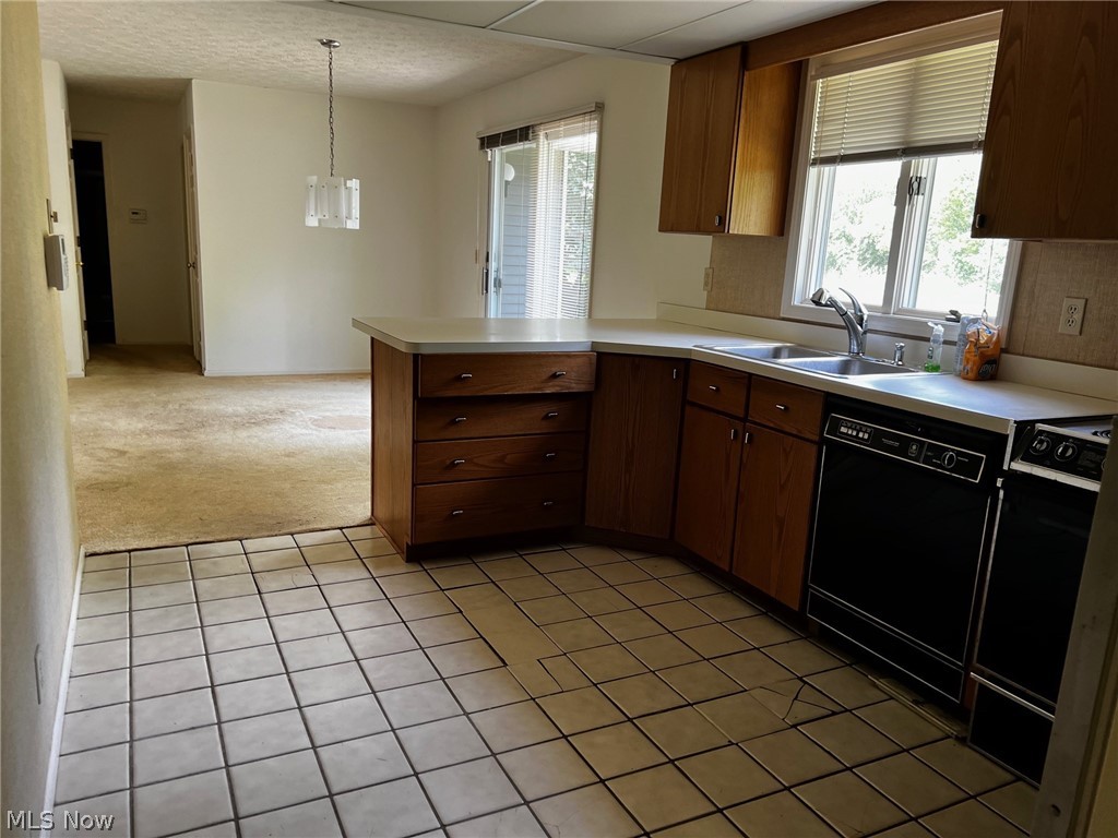 Kitchen featuring dishwasher, sink, light tile floors, and pendant lighting