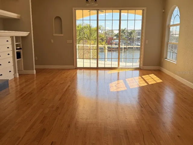a view of empty room with wooden floor and fan