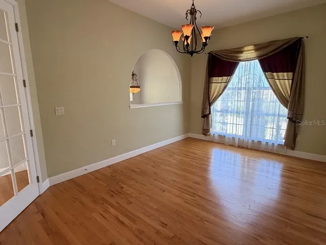 an empty room with wooden floor cabinet and windows