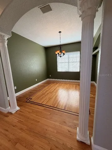a view of an empty room with window and wooden floor