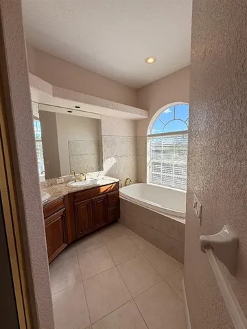 a bathroom with a granite countertop sink and a bathtub