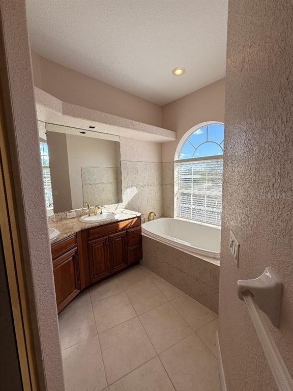 808 Symphony Isles Boulevard Apollo Beach, FL 33572 - Photo 44 of 50 a large bathroom with a granite countertop tub a sink and a large window