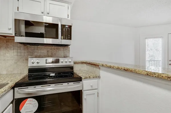 a view of kitchen with stainless steel appliances and cabinets