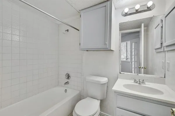 a bathroom with a toilet a sink a mirror a bathtub and vanity