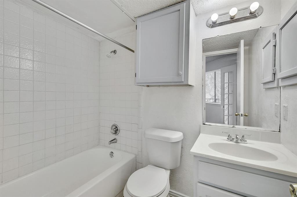 9823 Walnut Street, Unit 304 Dallas, TX 75243 - Photo 22 of 26 a bathroom with a toilet a sink a mirror a bathtub and vanity