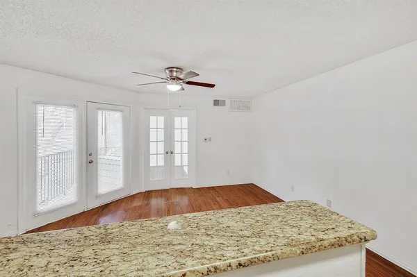 a view of a livingroom with wooden floor and kitchen view