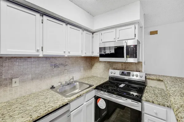 a kitchen with granite countertop a stove sink and microwave
