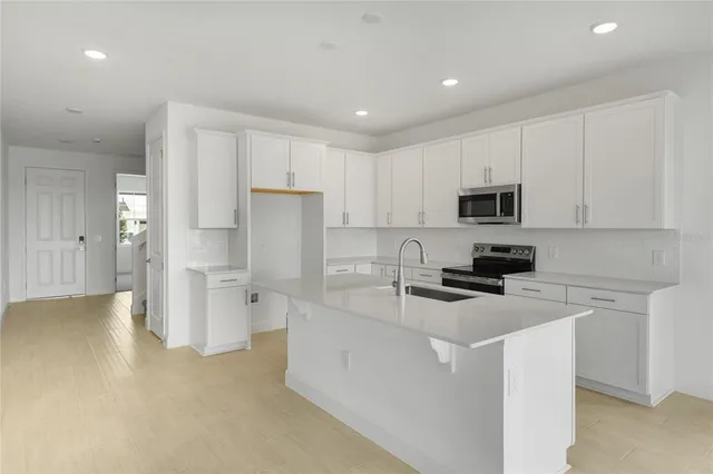 a kitchen that has a refrigerator a sink a stove a microwave and cabinets