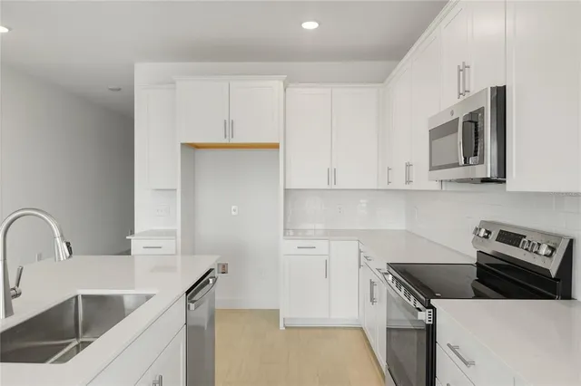 a kitchen with white cabinets sink and stainless steel appliances