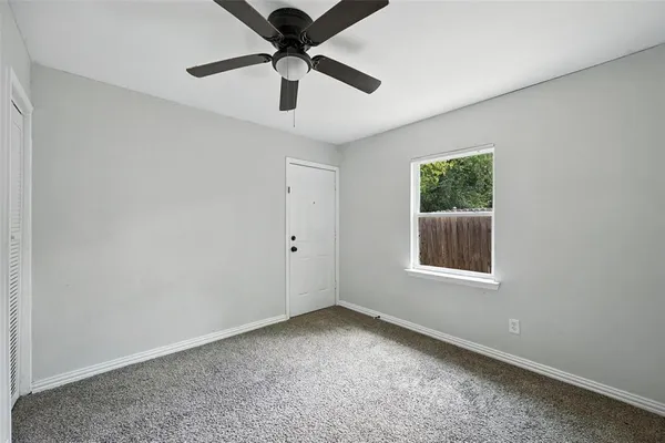 an empty room with a chandelier fan and windows