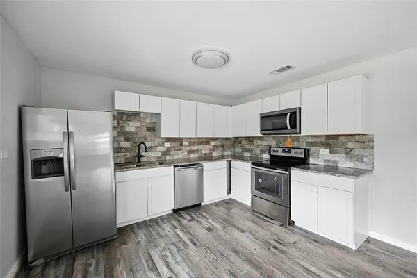 a kitchen with white cabinets and stainless steel appliances