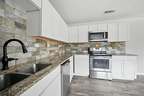 a kitchen with granite countertop a sink a stove and microwave
